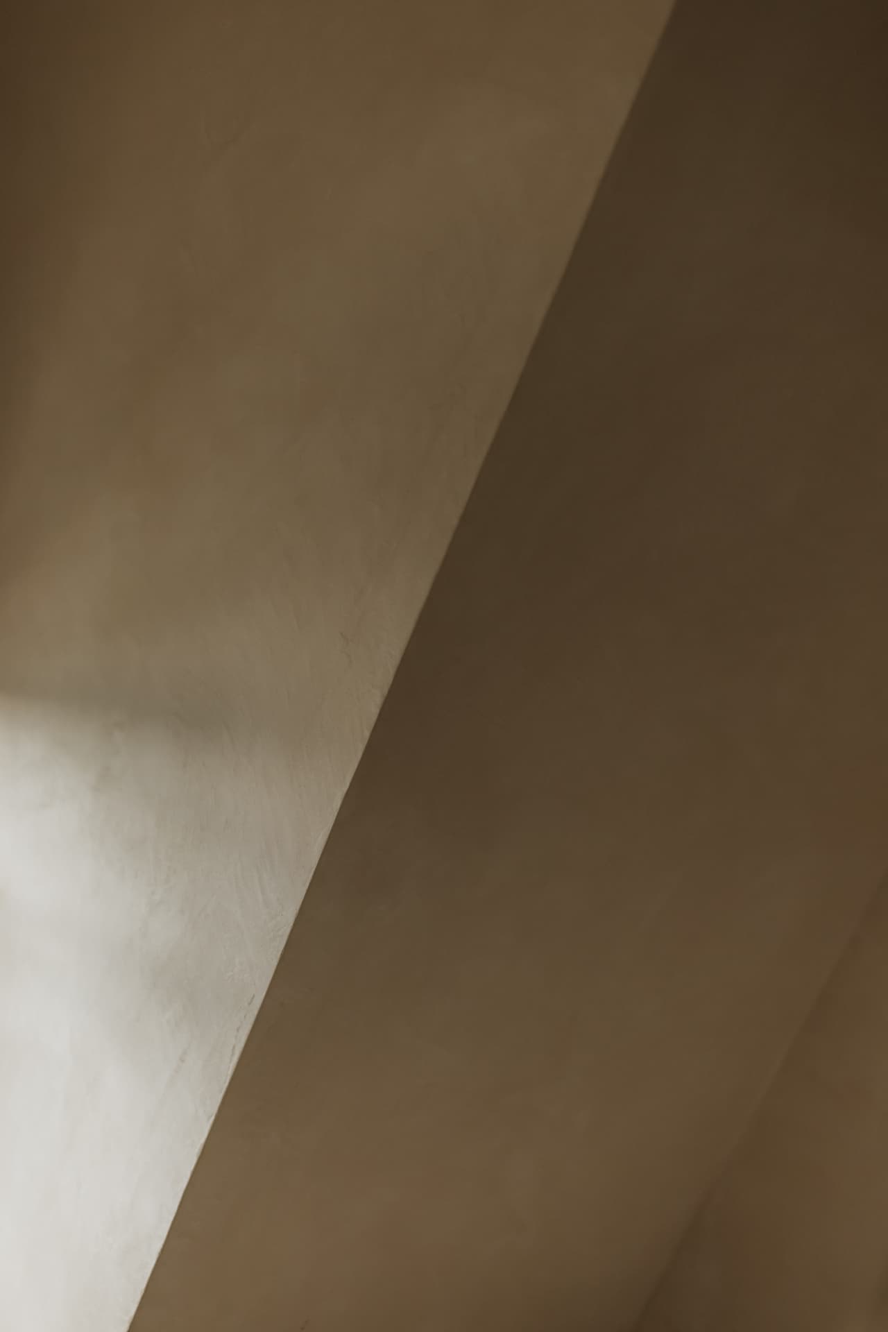 Warm plaster walls and ceiling meeting along a diagonal line of light and shadow