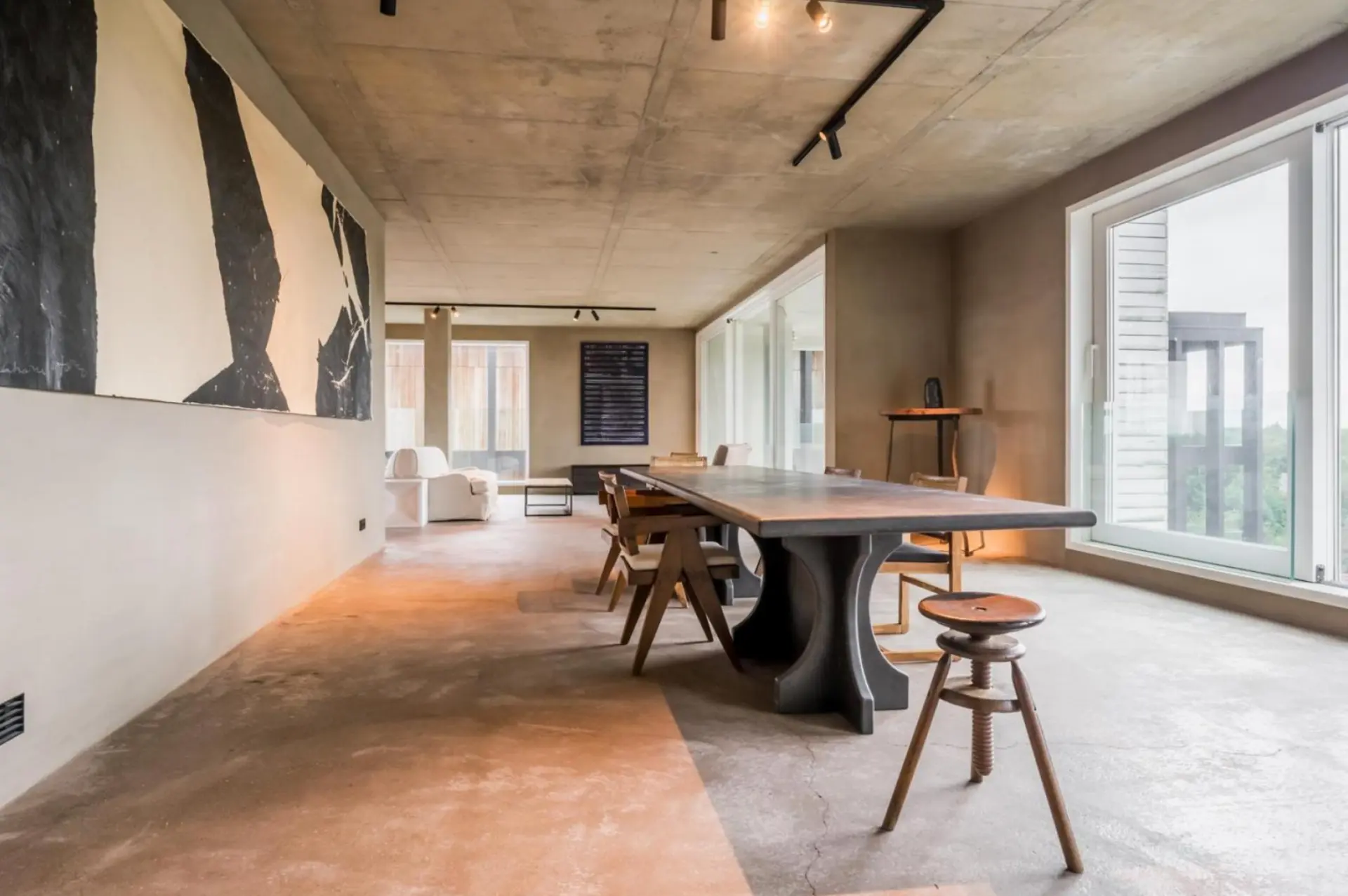 Dining area with a smooth mineral floor beneath an exposed raw concrete ceiling
